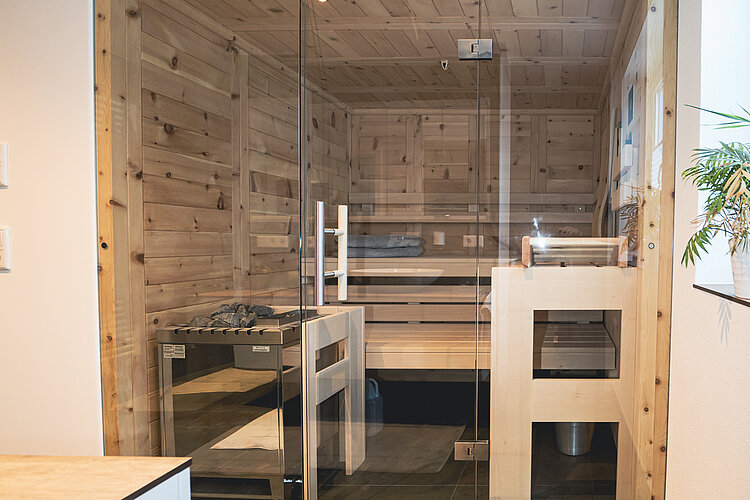 Moderne Heimsauna mit Glasfront, Holzverkleidung und Elektroofen in elegantem Wellnessbereich