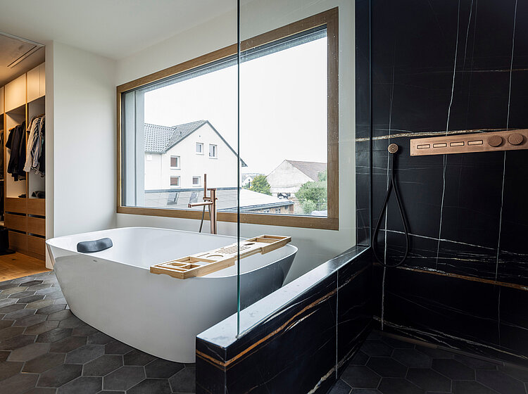 Freistehende Badewanne mit Holzablage und bodengleicher Dusche mit Kupferarmaturen in einem stilvollen Bad