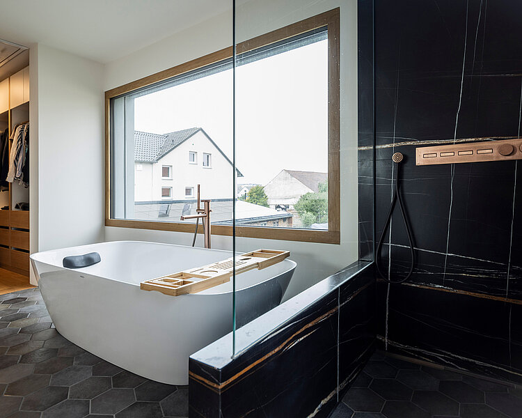 Freistehende Badewanne mit Holzablage und bodengleicher Dusche mit Kupferarmaturen in einem stilvollen Bad