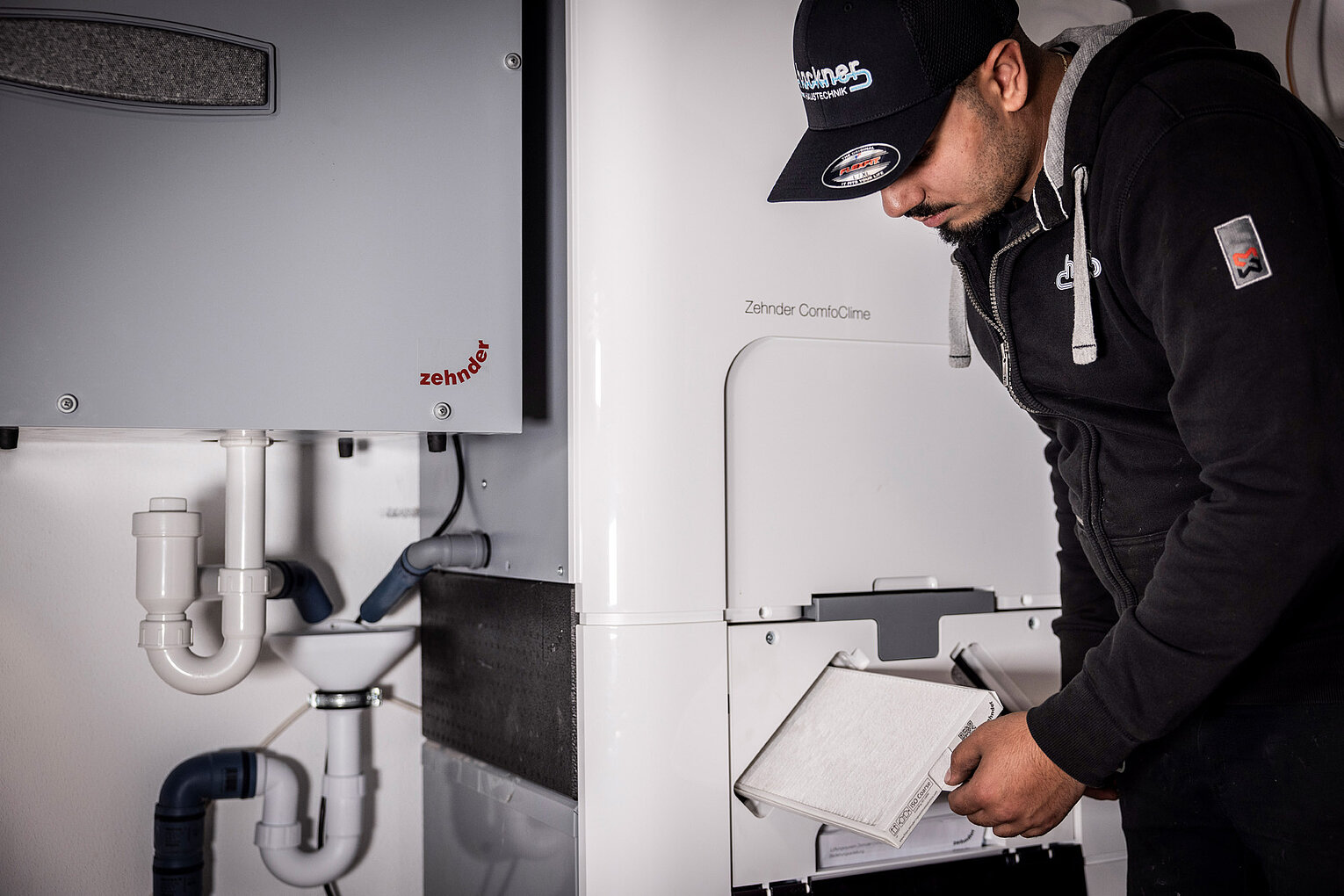 Techniker von Hackner Haustechnik wechselt einen Luftfilter an einem Zehnder ComfoClime Gerät