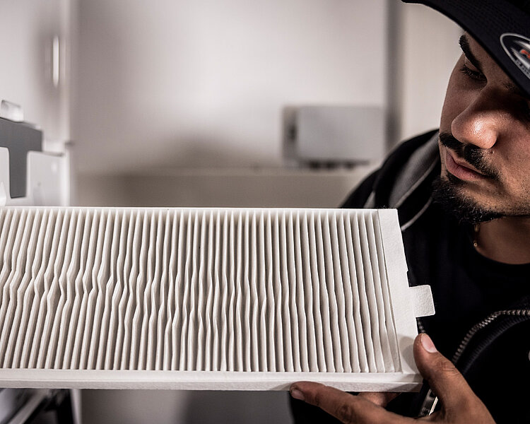Mitarbeiter von Hackner Haustechnik prüft einen weißen Luftfilter an einem Lüftungsgerät