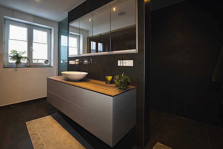 Modernes Badezimmer mit Holz-Waschtisch, Aufsatzwaschbecken, Spiegelschrank und Pflanzen