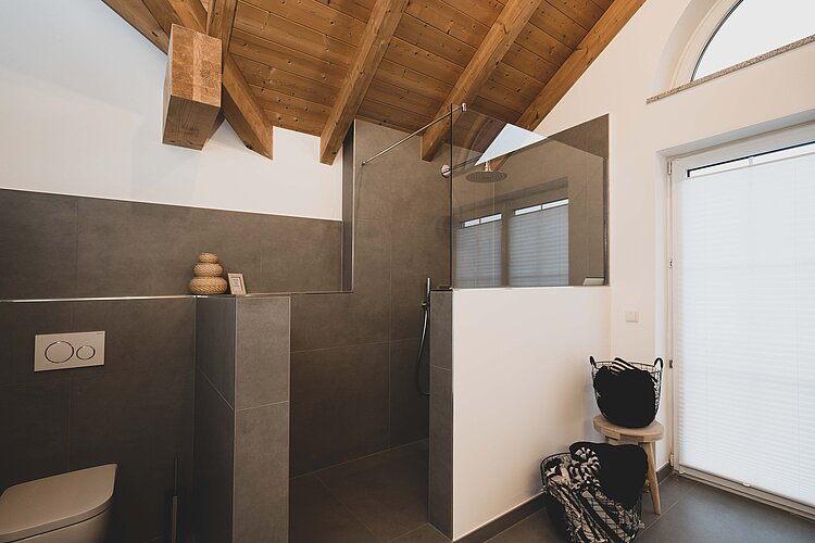 Badezimmer mit begehbarer Dusche, Holzdecke und natürlichen Materialien in harmonischer Kombination